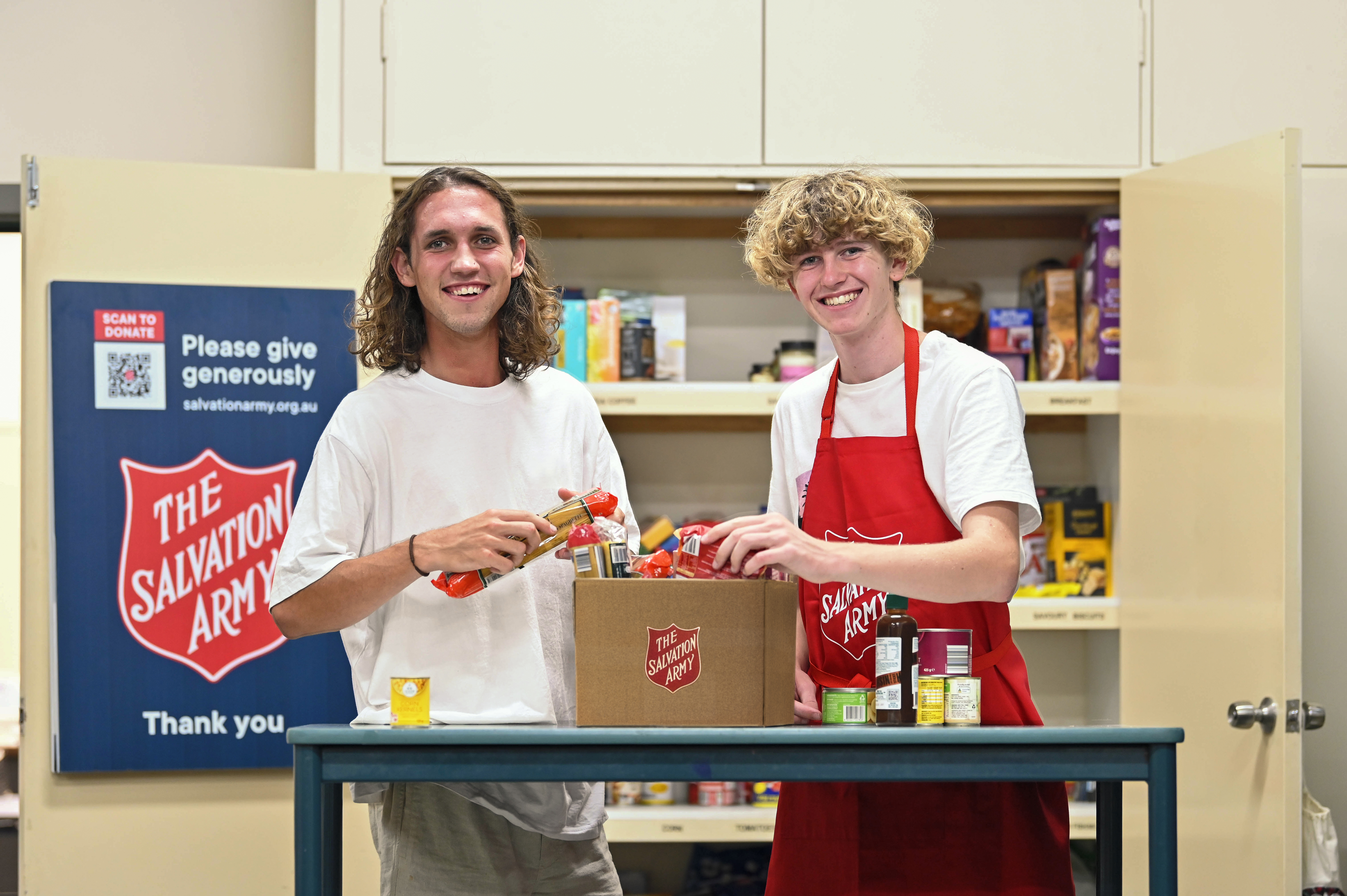 Two young people preparing food hampers for the community.