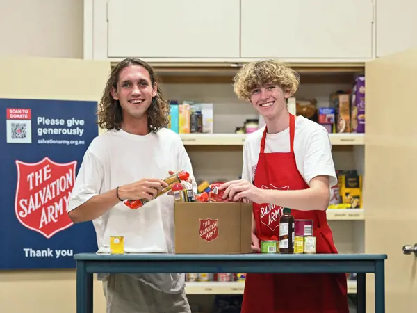 Two young people preparing food hampers for the community.